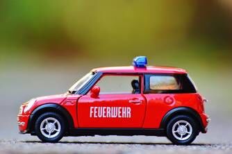 Ein Spielzeug-Feuerwehrauto steht auf einer Straße, Marke: Mini