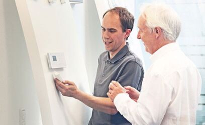 Patrick Thoms - Leiter Sicherheitstechnik bei Delphos im Showroom erklärt einem älteren Mann eine Alarmanlage.