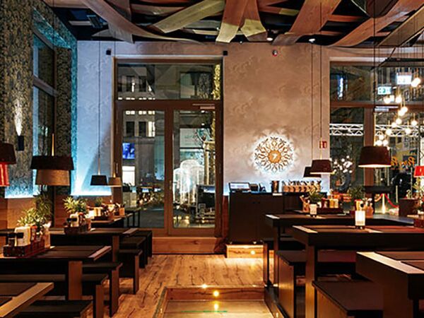 Das Restaurant Peter Pane von innen. Links hintereinander mehrere gemütliche Esstische. Rechts eine weitere Tischreihe und die Bar.