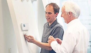 Patrick Thoms - Leiter Sicherheitstechnik bei Delphos im Showroom erklärt einem älteren Mann eine Alarmanlage.