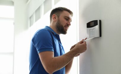 Mann installiert Haussicherheitssystem an weißer Wand im Zimmer